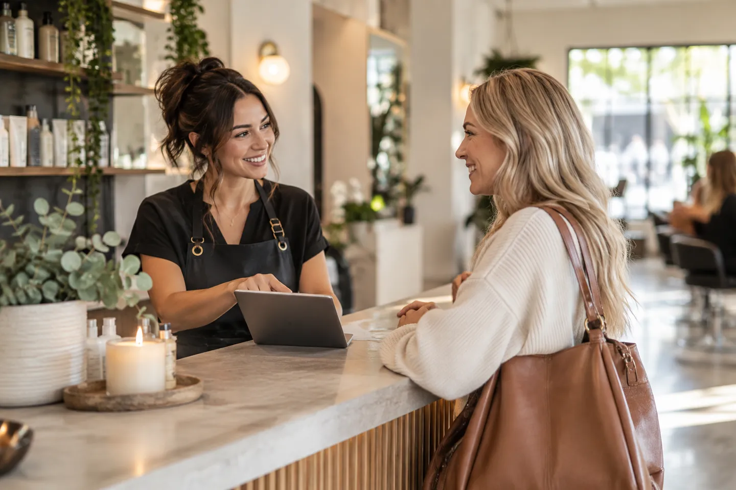 A receptionist discussing the next visit with a satisfied client at checkout in a bright boutique salon